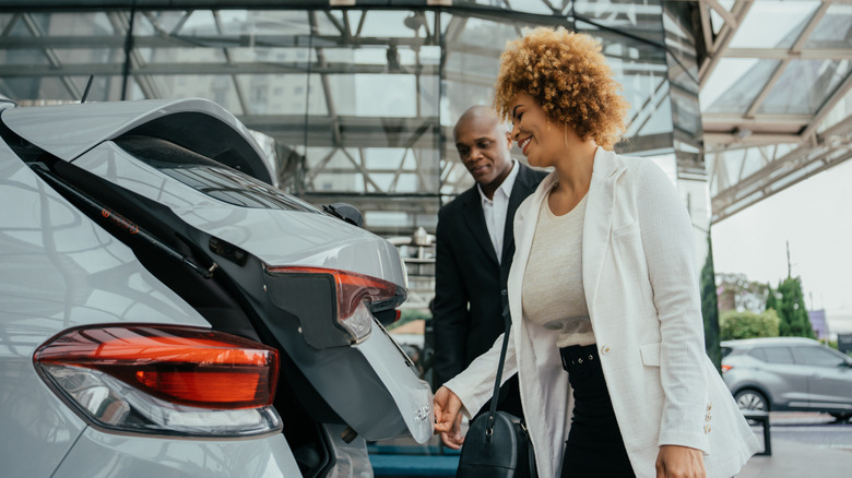 A young woman opening the trunk of a rental car