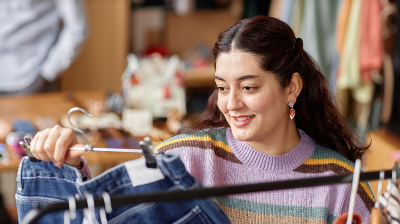Smiling woman looking at secondhand jeans for sale