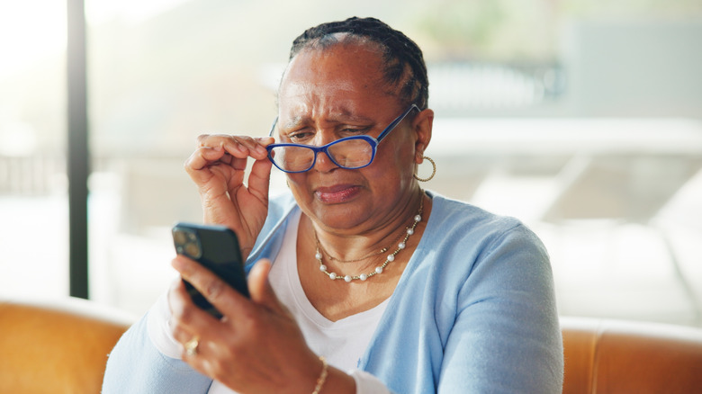 Olded woman looking upset as she checks her phone