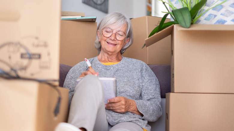 Older woman surrounded by a boxes, planning a move