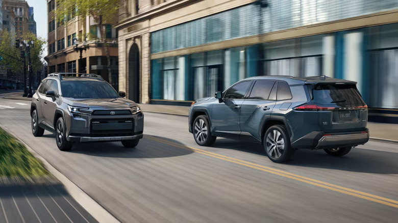 a blue and a silver Toyota RAV4 pass each other on a city street