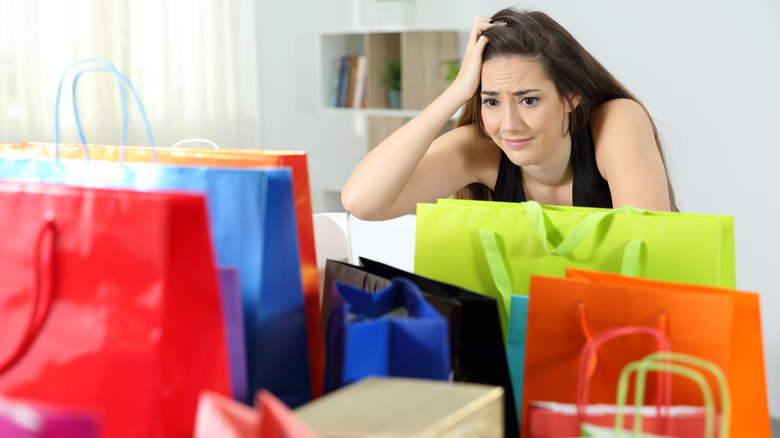 Woman after multiple purchases in colorful shopping bags at home