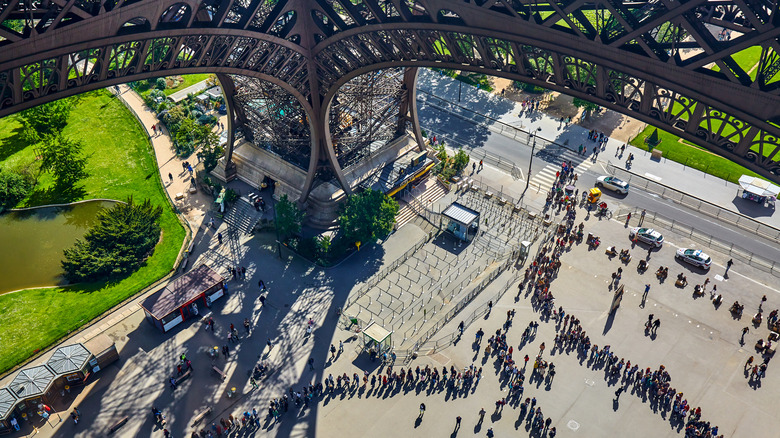 Massive lines of people queue up under the Eiffel Tower