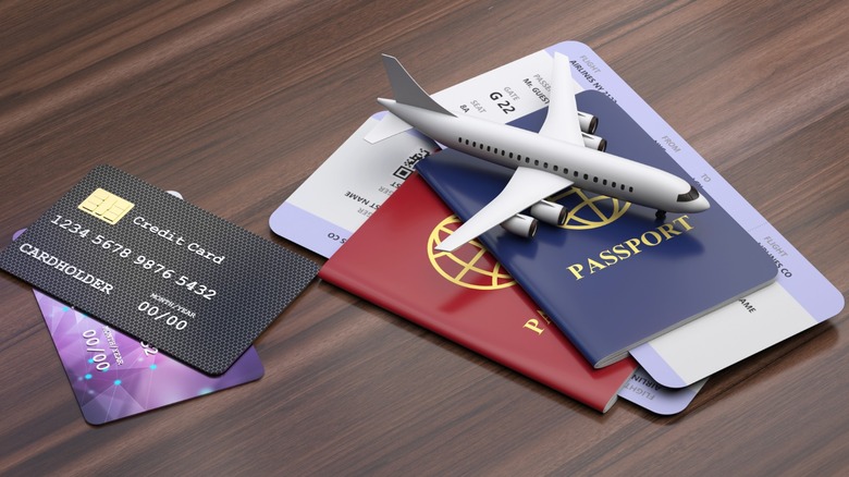 Credit card beside passports, airline boarding passes, and a model airplane on a wooden surface, representing booking and paying for air travel