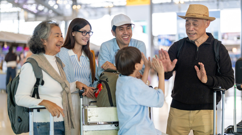 A happy multigenerational family together at the airport with luggage.