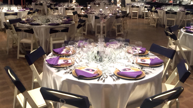 A close up of a banquet hall table with plates,cutlery and wine glasses.
