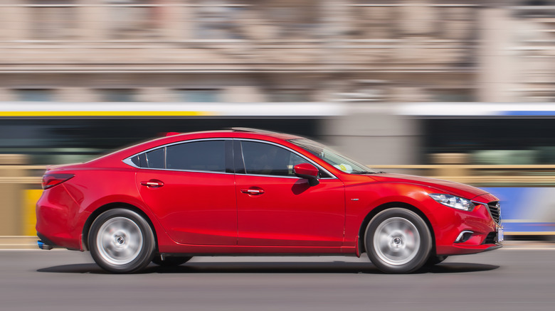 A red Mazda 6 vehicle driving quickly down a street.