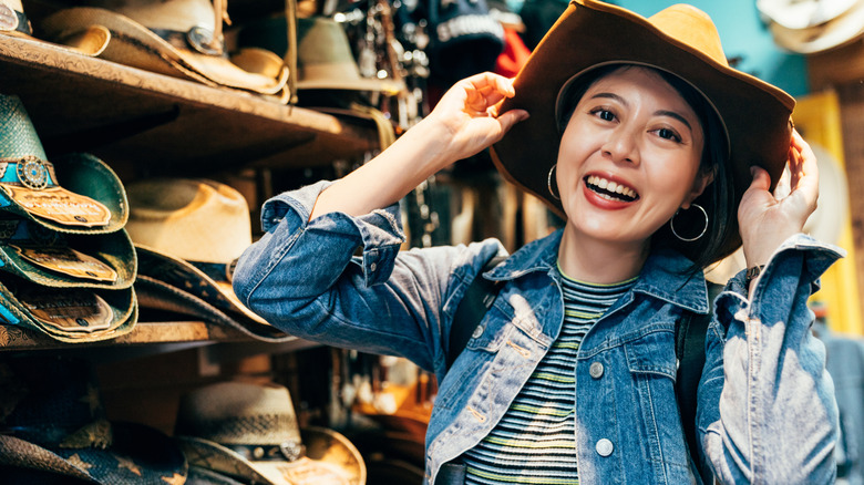 A happy woman trying on a cowboy hat in a store