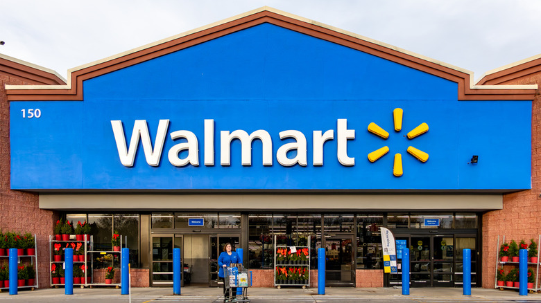 A woman pushing a shopping cart outside a Walmart entrance