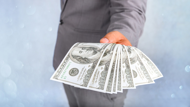A man holding several $100 bills