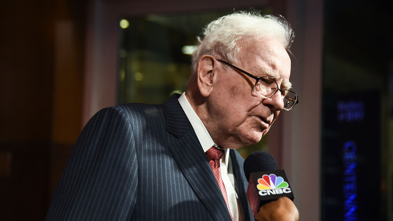 Warren Buffett speaking on a microphone