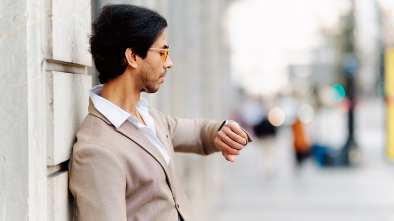 man standing in city looking at his watch