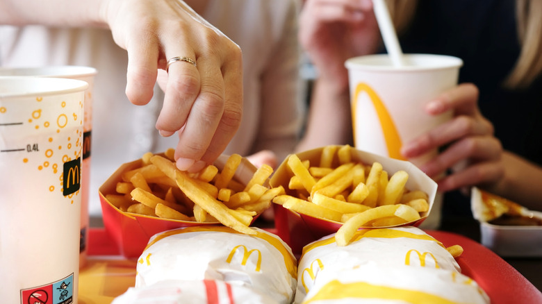 Hands reaching to grab McDonald's food on a tray.