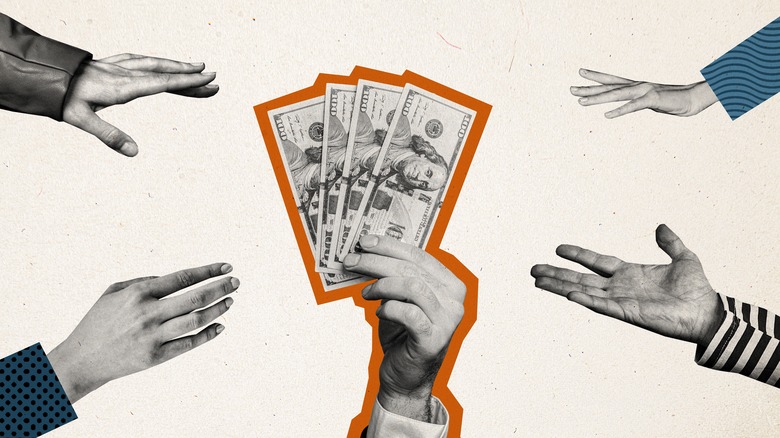 Multiple hands all reach for same stack of money