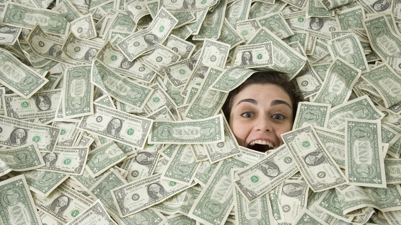 Woman happily buried in a pile of $1 bills