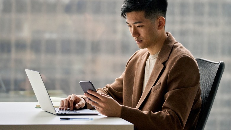 Person on laptop reviewing phone