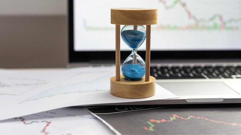 Hourglass with computer, financial papers