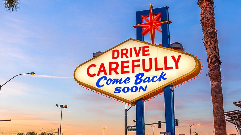 Las Vegas sign with palm trees reads 'drive carefully' and 'come back soon'