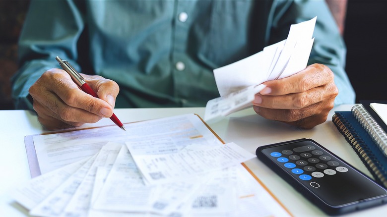 Person holding pen, crunching numbers