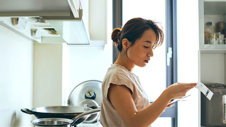 Person in kitchen reviewing receipt