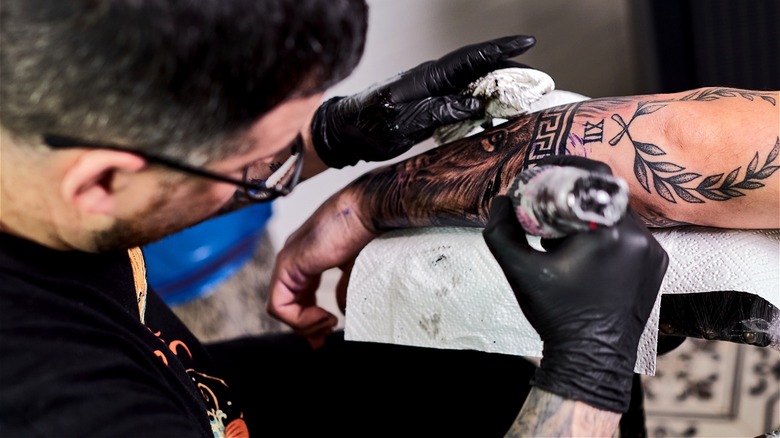 Person getting tattooed at shop