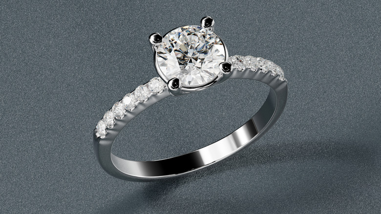 Close up of large white diamond set in silver or platinum ring fitted with multiple smaller white diamonds