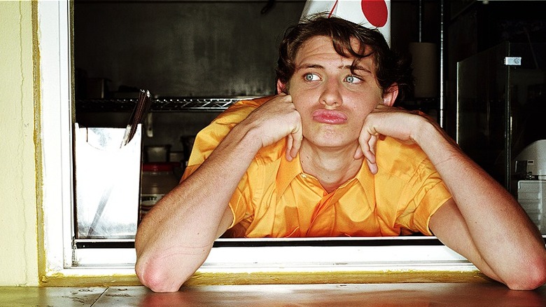 A teenage fast-food worker waits for customers at window