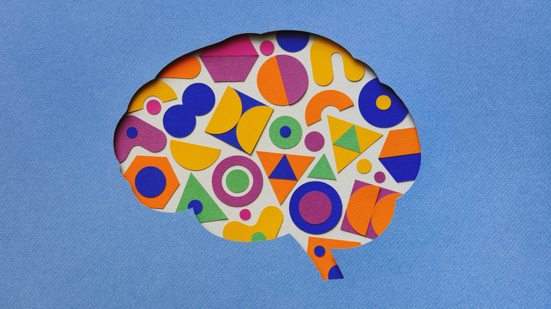 Paper craft illustration of brain filled with multi colored geometric shapes.