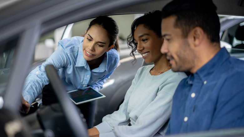 salesperson speaking with buyers in car