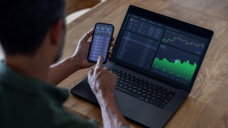 Man adjusting portfolio on computer and phone.