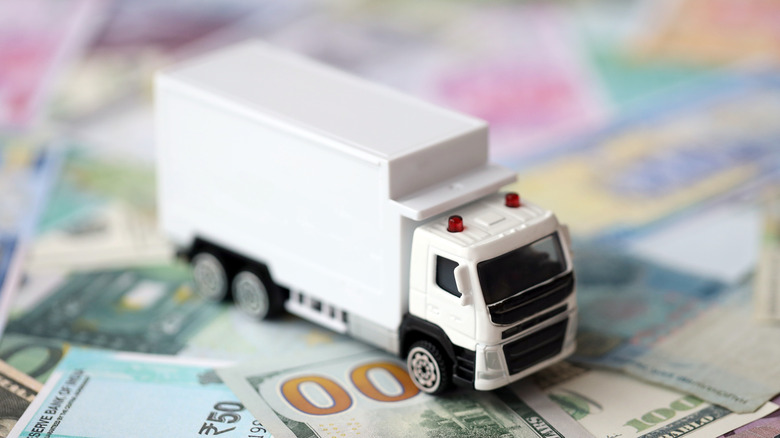Toy moving truck resting on dollar bills of various values