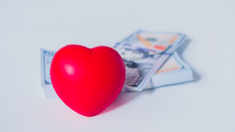 Red heart toy in front of hundreds of dollars