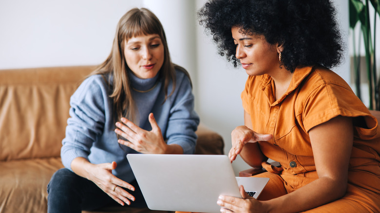Two women looking at laptop and talking.