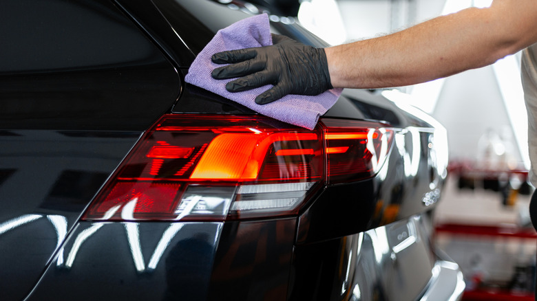 Professional man wiping back of car with a microfiber cloth.