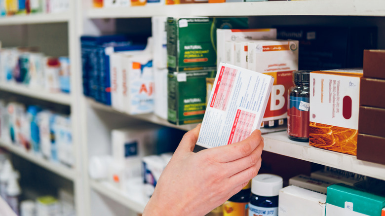 Person arranging medications on a store shelf