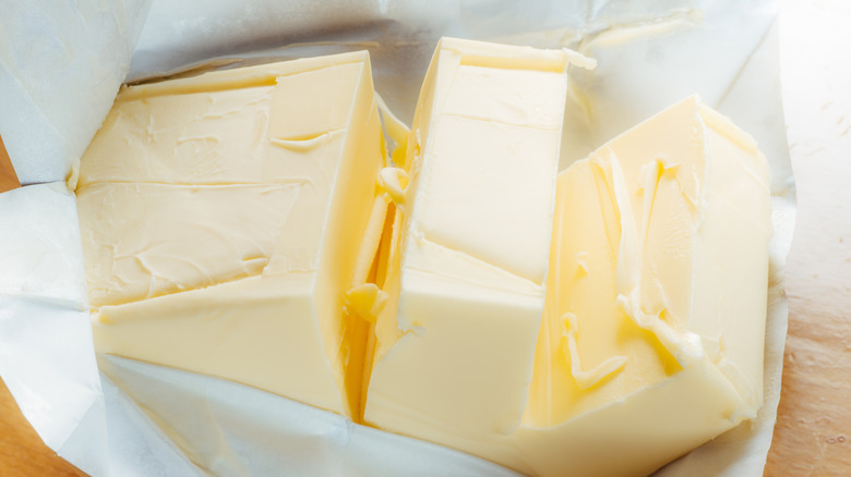 An unwrapped block of butter sliced into chunks.
