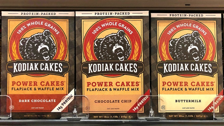 Three boxes of Kodiak Cakes flapjack and waffle mix on grocery story shelf