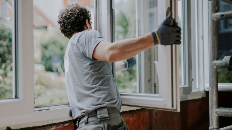 Man replacing a window in a home