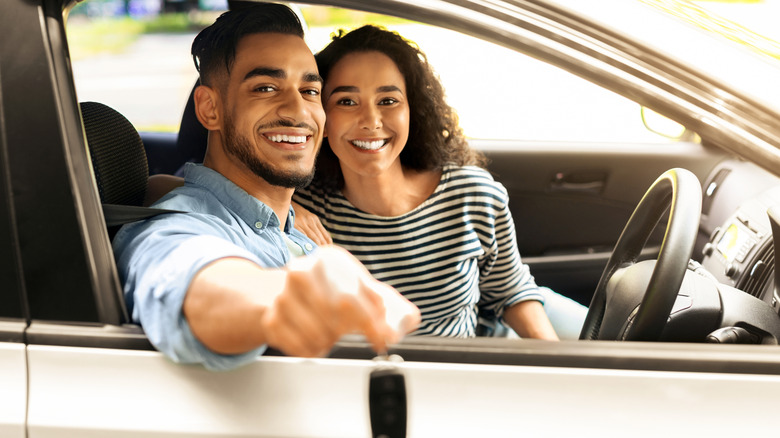 Couple in car with driver hold key out of window