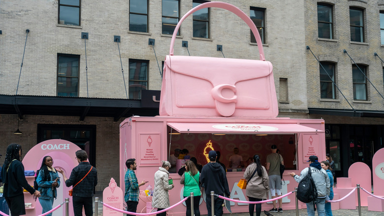 Shoppers mill around a giant pink Coach tabby bag display in New York City