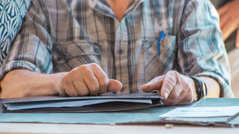 Elderly man with folder of documents on desk