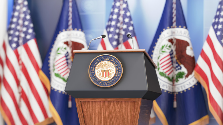 Podium in front of U.S. and Federal Reserve flags.