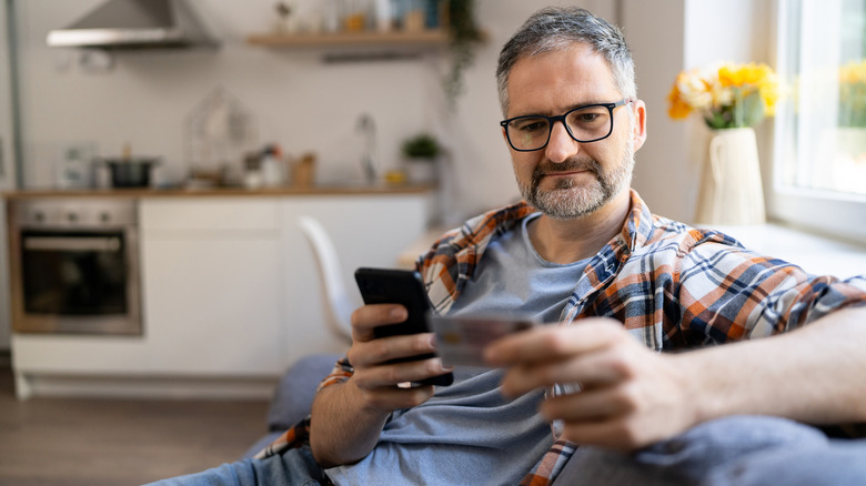Man typing his Social Security number over a mobile phone from home.