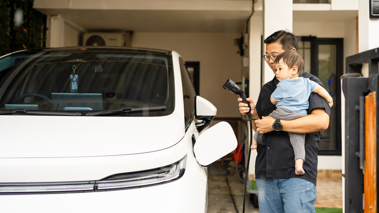 Father and child plugging an EV into a charging station at home