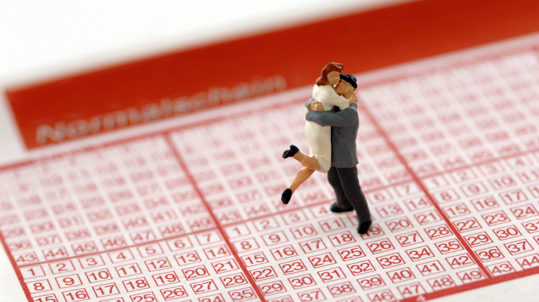 figurines hugging on a lottery ticket