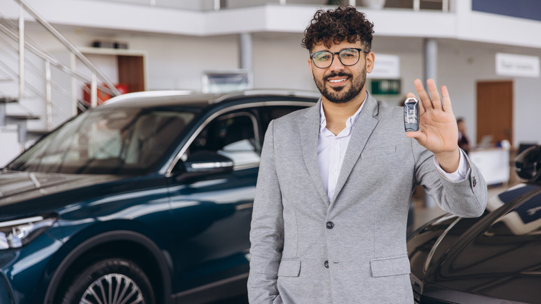 A man holding a car key in a dealership