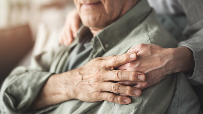 older man with hand on his shoulder