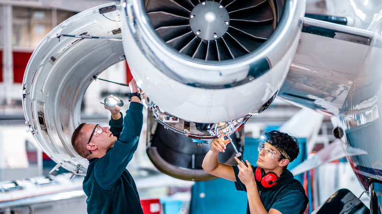 Two mechanics repairing a plane
