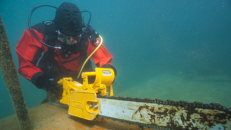 An underwater diver using a chainsaw