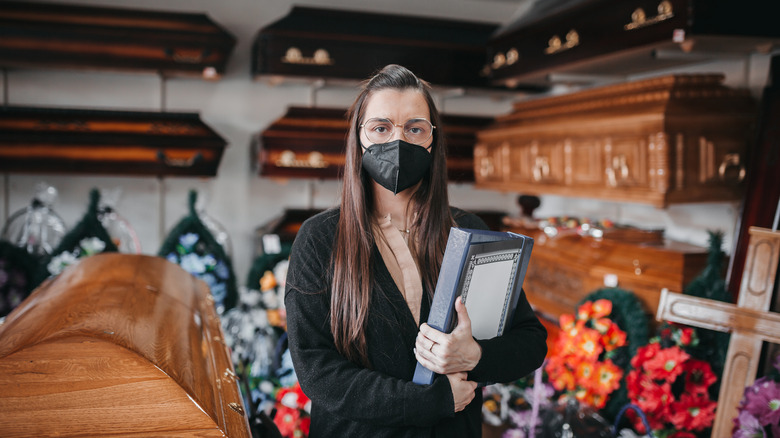 A woman standing among coffins
